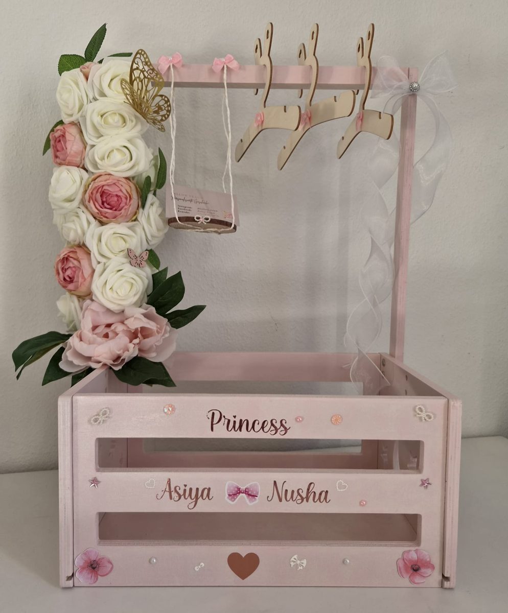 Personalisierter Geschenkholzkorb in Rosa mit Kunstblumen, Kleiderbügeln und Namen